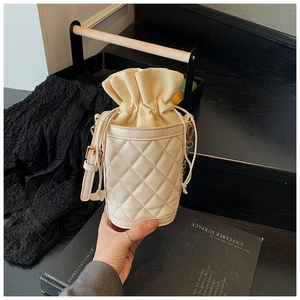 Detail of white quilted bucket bag with cream canvas drawstring and gold metal buckle