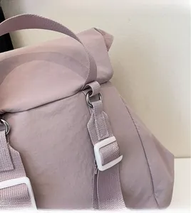Detail of adjustable woven shoulder strap and metal hardware on lilac canvas backpack