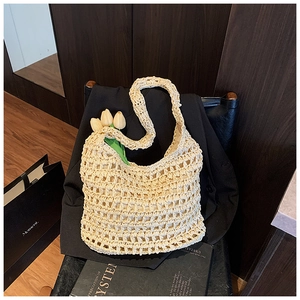Detailed view of beige hollow woven straw tote bag featuring decorative yellow tulips