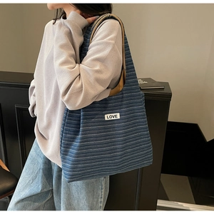 Detail of blue striped canvas tote bag with LOVE label and long khaki shoulder strap