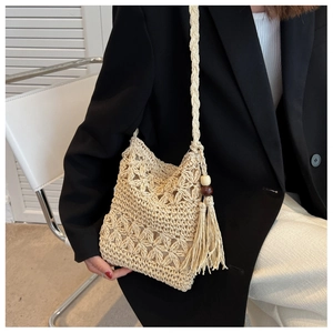 Detailed close-up of hollow flower weave and tassel with wooden beads on straw bag