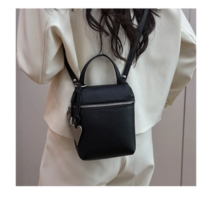 Detail of black litchi texture square bag with silver hardware and heart pendant