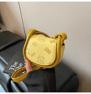 Detail of a bright yellow saddle bag featuring cute cartoon bear prints and leather texture