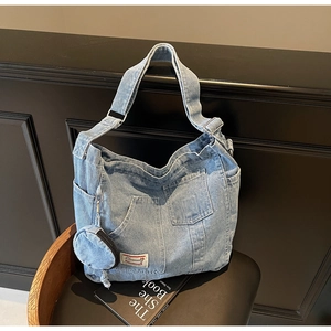 Detail of light blue denim tote bag with functional pockets and detachable coin purse