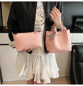 Detailed view of pink pebble grain leather bucket bag set with bow charm and pouch