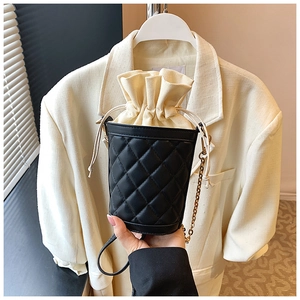 Detailed view of black quilted bucket bag with gold chain strap and drawstring inner pouch