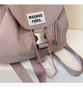 Detailed close-up of light purple canvas backpack with silver buckle and woven brand label