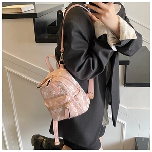 Mini pink textured faux leather backpack with gold hardware shown on a black suit jacket