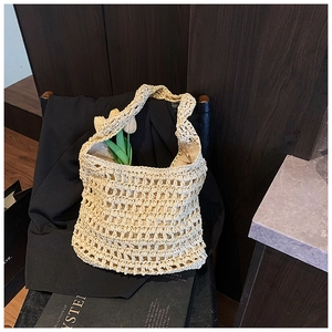 Detailed close-up of cream handmade woven tote bag with hollow hollow mesh texture on black leather