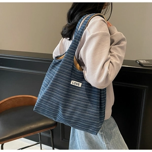 Detail of blue striped tote bag with LOVE patch shown in casual lifestyle setting