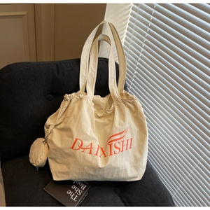 Detail of beige canvas tote bag with orange logo and matching small round zipper pouch