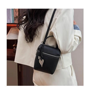 Détail du mini sac seau noir en cuir grainé avec pendentif coeur sur modèle
