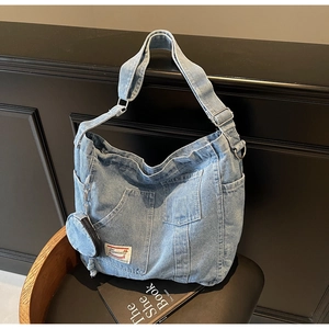 Detail of blue denim tote bag with multiple pockets, adjustable strap and coin purse
