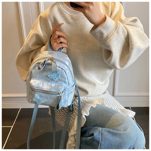 Detail of light blue jacquard backpack with floral texture and butterfly appliques