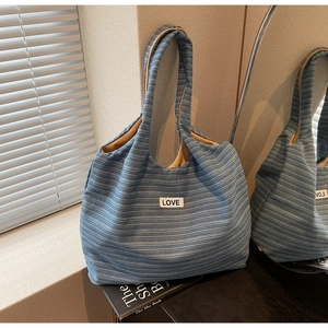 Detail of blue and white striped tote bag with LOVE patch on woven fabric surface