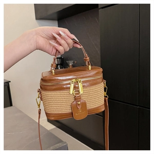 Close-up of brown leather and straw weave mini box bag with gold-tone hardware and logo tag