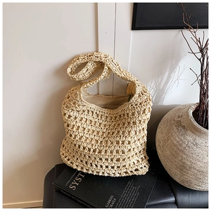 Detail of hollow-out hand-woven pattern on large cream straw shoulder bag for beach