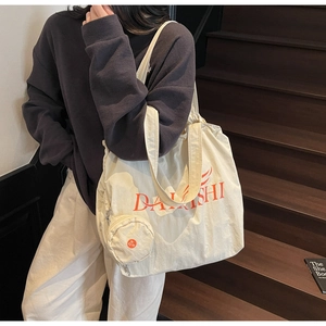Detail of off-white canvas tote bag with DAKISHI print and matching round coin purse