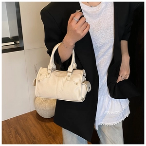 Dettaglio della borsa Boston in pelle color crema con borchie e tasche laterali a patta