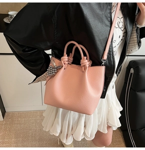Pink lychee grain bucket bag featuring a knotted handle and silver bead tassel pendant