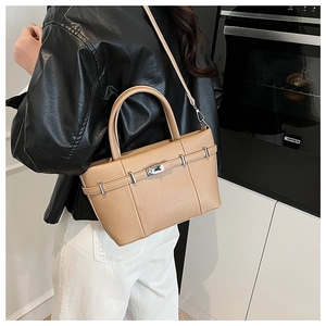 Sac seau beige texture litchi avec détails argentés porté en bandoulière sur modèle