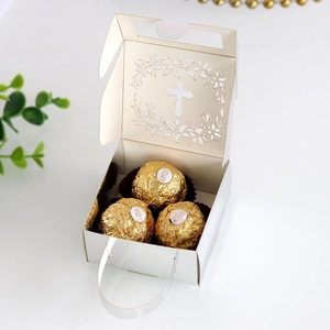 Detailed view of laser-cut white cross candy box with ribbon handle and chocolates