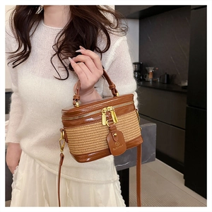 Detail view of woven mini bucket bag with dark brown patent leather trim and gold hardware