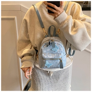 Close-up of light blue backpack with white floral embroidery and 3D butterfly appliqué