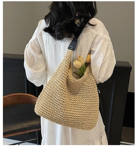 Close-up of hand-woven straw tote bag with black strap and decorative yellow tulips