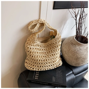 Detailed macro view of the hand-woven hollow crochet texture on this beige straw tote bag