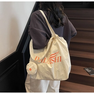 Detail of cream canvas tote bag with orange graphic and matching coin purse on stairs