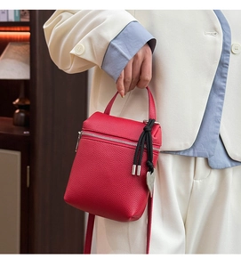 Détail d'un mini sac en cuir rouge texturé avec pendentif coeur et pompon élégant
