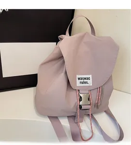 Close-up of pink drawstring backpack featuring a metal buckle and white woven label detail