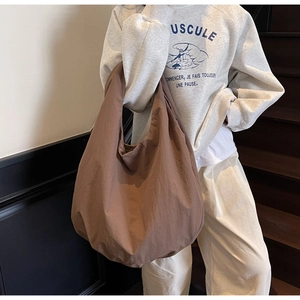 Dettaglio di una borsa tote marrone in tessuto con pieghe eleganti indossata da modella