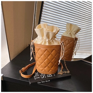 Detailed view of brown quilted bucket bag with drawstring liner and gold chain strap