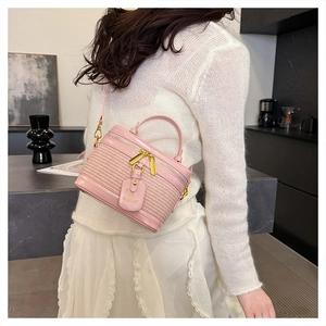 Detailed close-up of pink woven box handbag with gold hardware and leather top handle