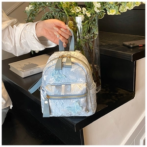 Detail of light blue jacquard mini backpack with butterfly embroidery on marble
