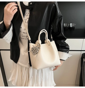 Close-up of off-white lychee texture bucket bag with silver grape bead charm detail