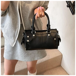 Dettaglio della borsa in pelle nera a grana con borchie metalliche decorative