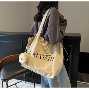 Detail of a large beige canvas tote bag with a matching mini pouch shown on a model