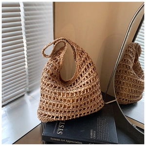 Detail showing handwoven hollow-out texture and thick handle of the straw tote bag