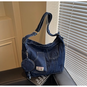 Detail of dark blue washed denim shoulder bag with multiple utility pockets and small pouch