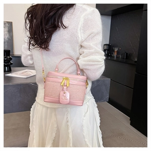 Close-up of pink woven texture box bag with gold metal hardware and brand tag detail