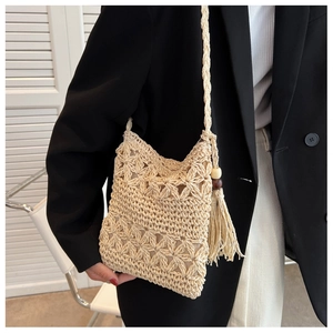 Détail du sac à bandoulière en paille tressée avec franges bohèmes et perles de bois