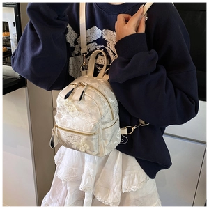 Detail of floral lace embroidery and gold metal zippers on this mini cream backpack
