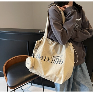 Detail of beige drawstring tote bag with letter print and matching mini coin purse