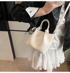 Close-up of a cream knotted handle crossbody bag with a silver sphere charm detail