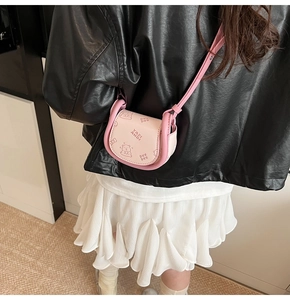 Pink saddle bag with cute cartoon bear print shown on a model in a casual outfit