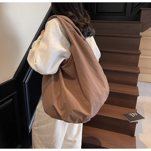 Dettaglio della grande borsa hobo marrone indossata, con texture in tessuto sintetico opaco