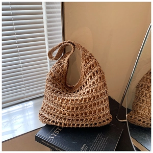 Detail of hollow-out mesh straw tote bag with inner pouch on artistic background